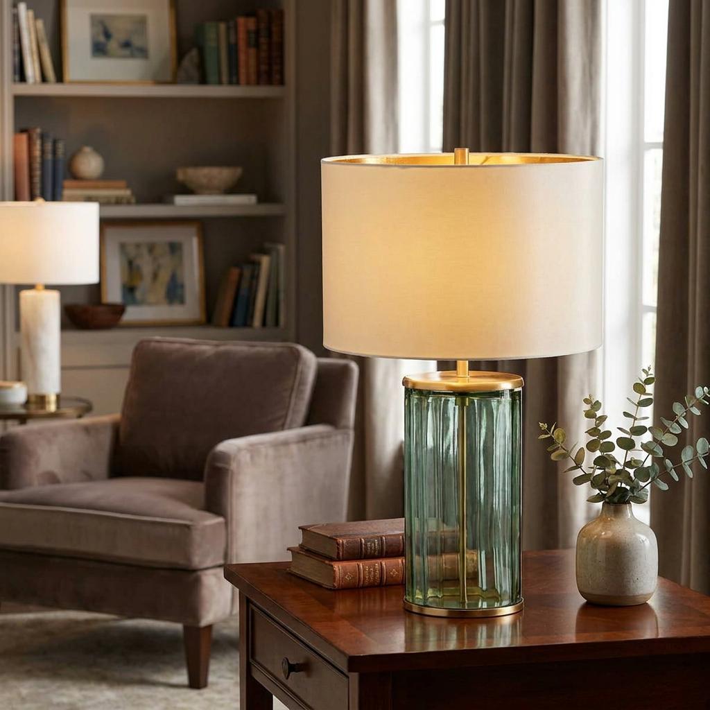 Reno green glass and aged brass table lamp with a cream shade on a wooden side table in a cozy living room.
