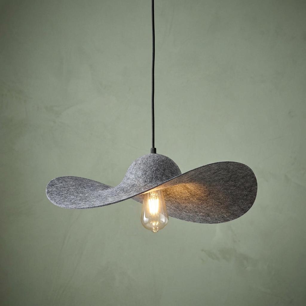 A gray felt ripple pendant light with a black cord and glowing filament bulb against a pale green wall.