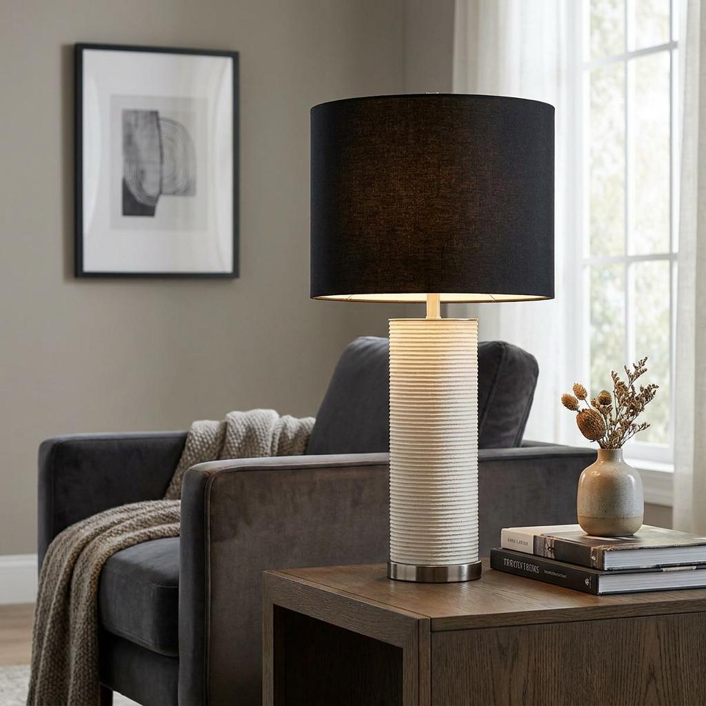 Ripple white table lamp with a black drum shade on a wooden side table in a modern living room.