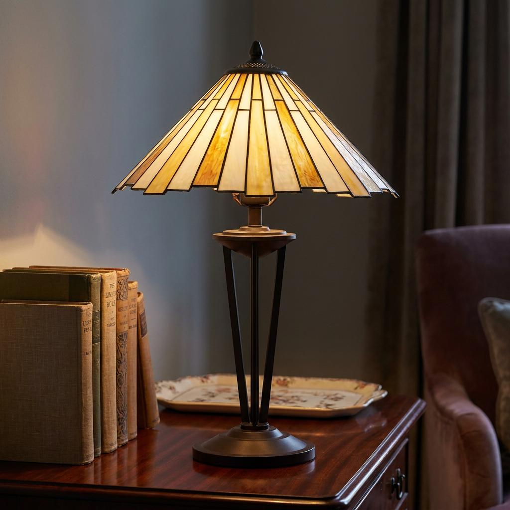 Art Deco Tiffany lamp with an amber sunburst shade on a wooden table beside vintage books.