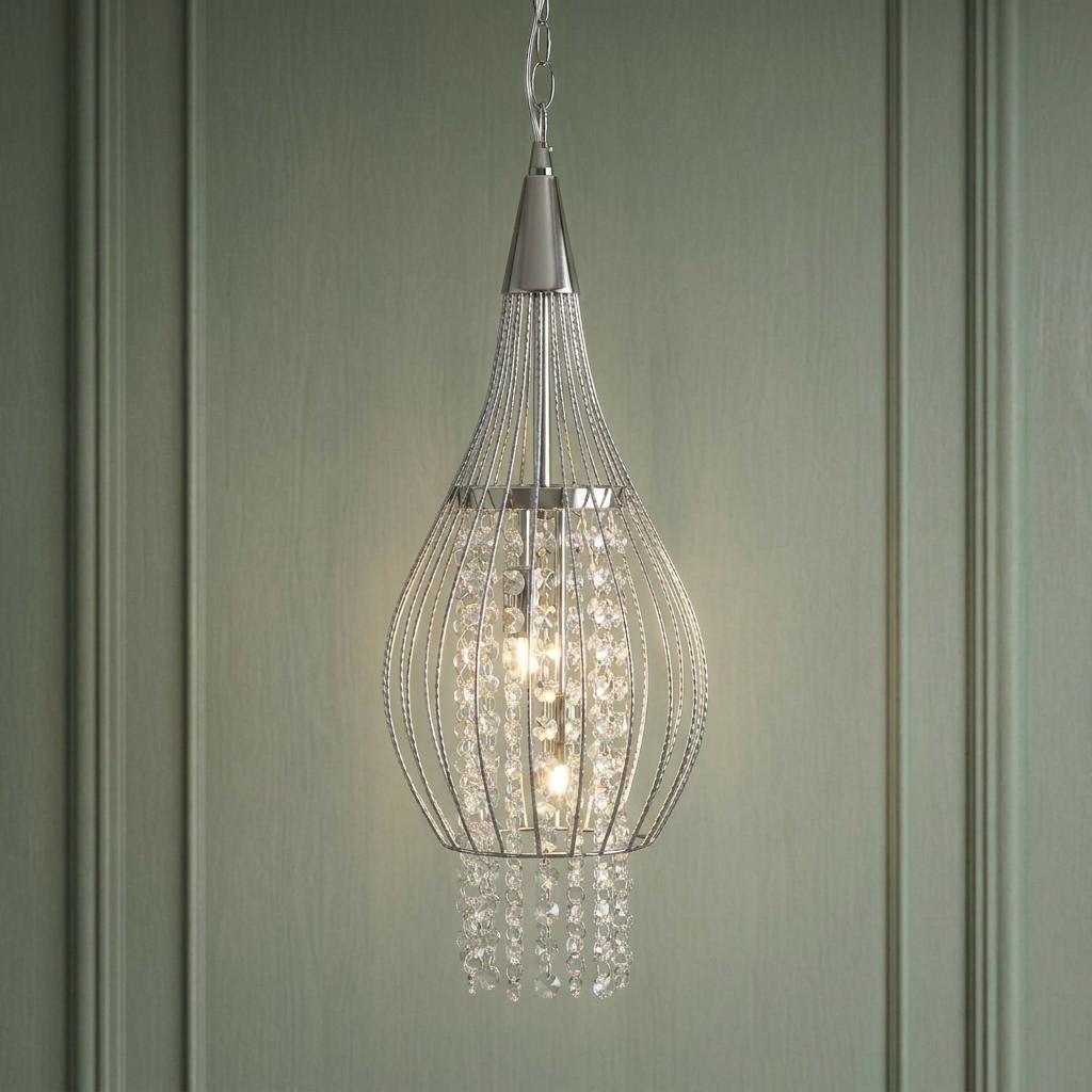 Chrome cage frame ceiling pendant with internal crystal strings and two lit bulbs against a green paneled wall.