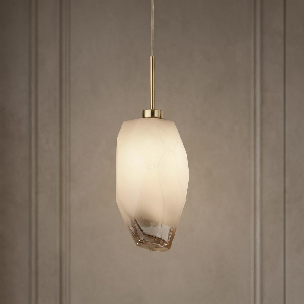 Satin brass pendant light featuring a frosted geometric glass shade with an amber base, hanging against a paneled wall.