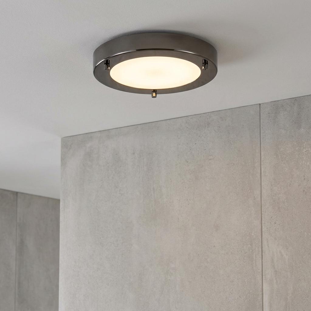 Rondo Mirror Black flush bathroom ceiling light with an opal glass diffuser against a grey stone wall.