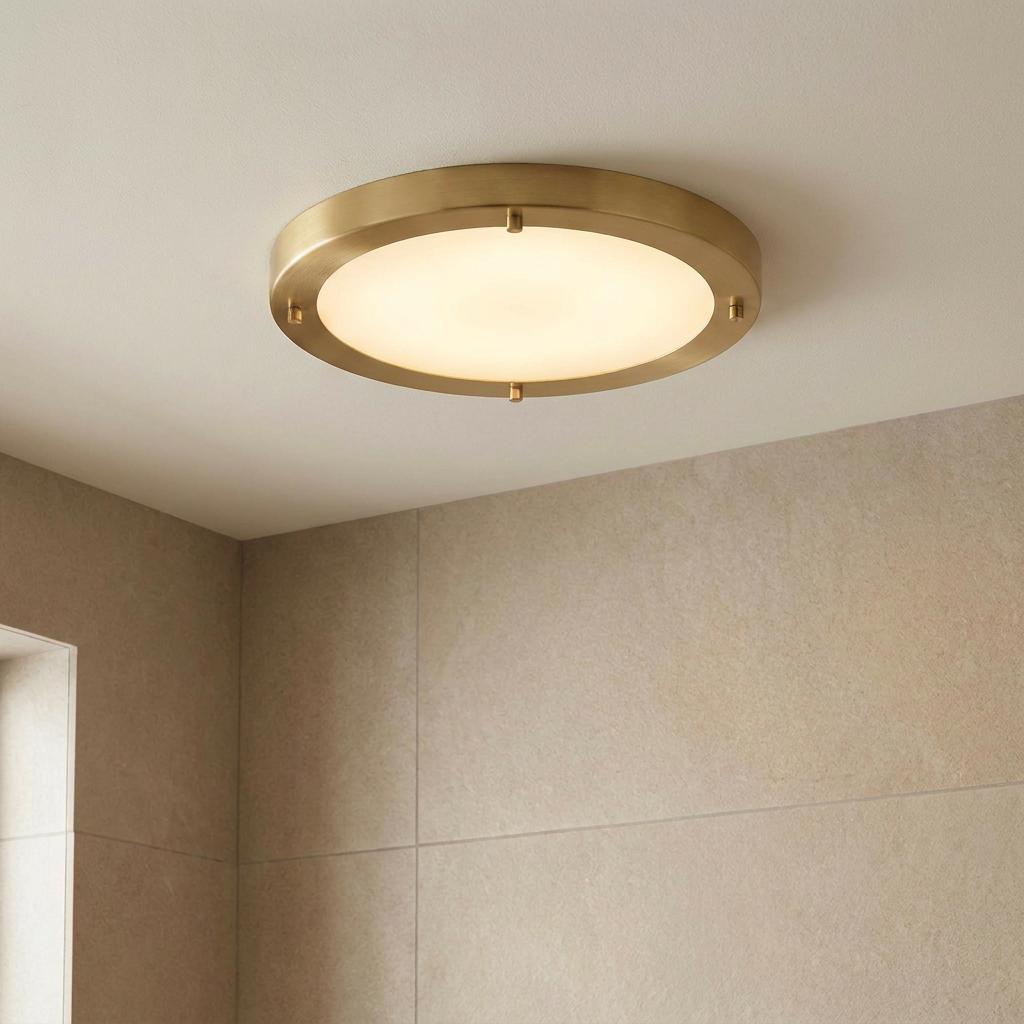 Large circular Rondo flush ceiling light in satin brass finish with a warm opal glow on a bathroom ceiling.