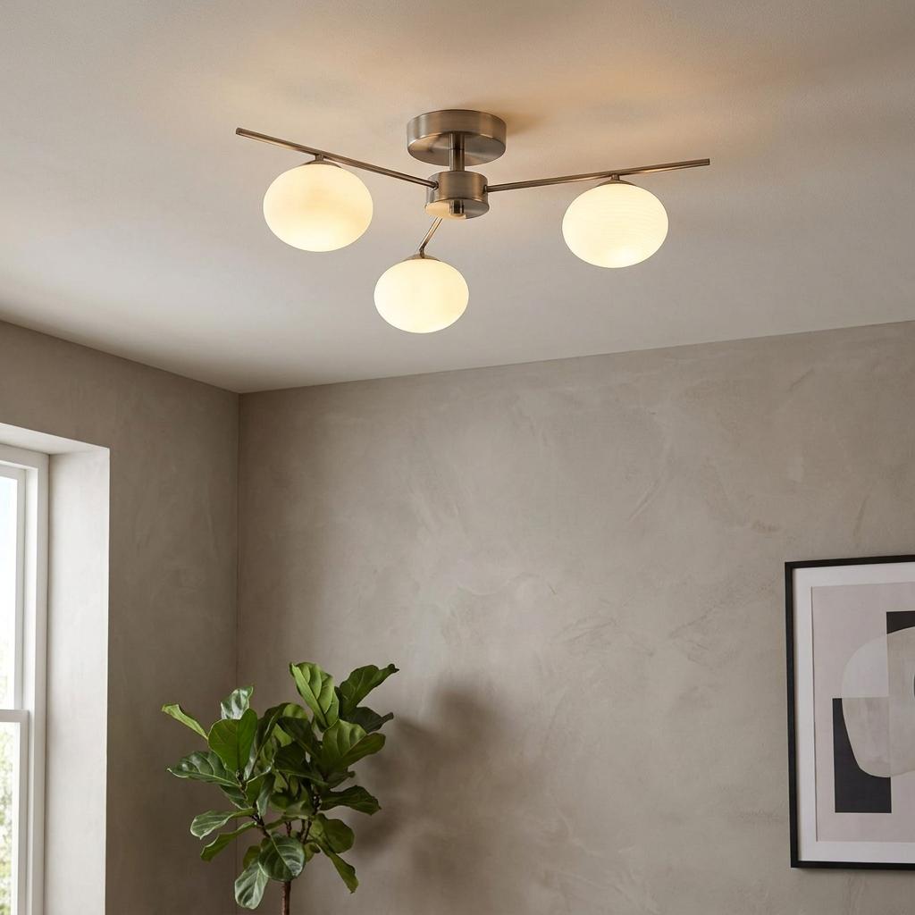 Three opal glass globes on antique chrome arms of a semi-flush ceiling light in a neutral-toned room.