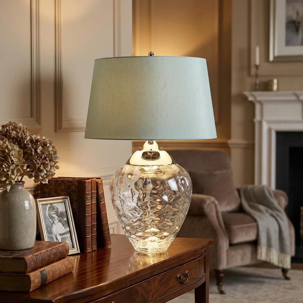 Samara clear textured glass table lamp with a light blue shade on a wooden table in a classic living room.