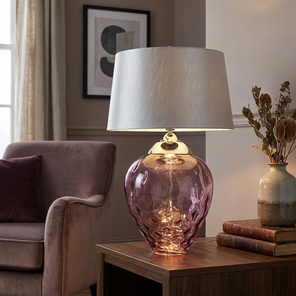 Samara large plum glass table lamp with a silver shade on a wooden table in a living room setting.