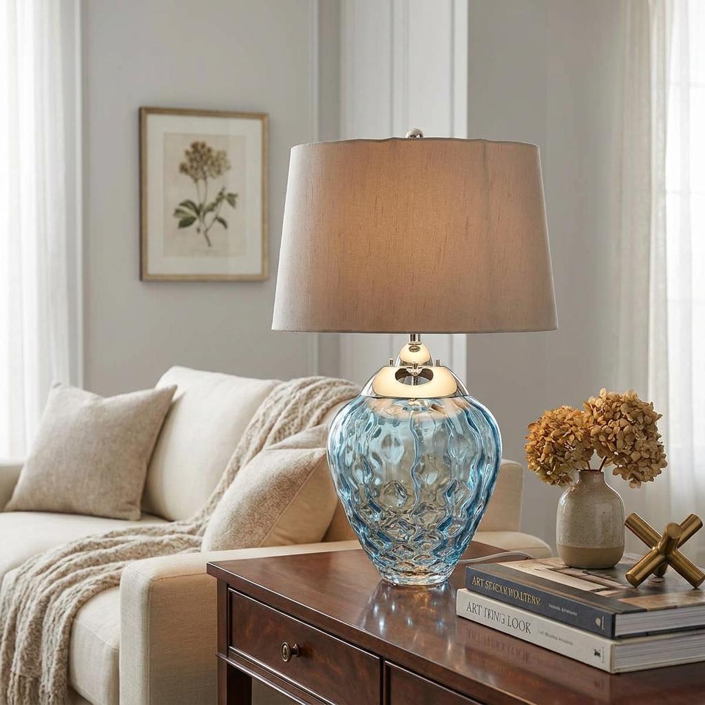 Samara light blue dimpled glass table lamp with a beige fabric shade on a wooden side table in a living room.