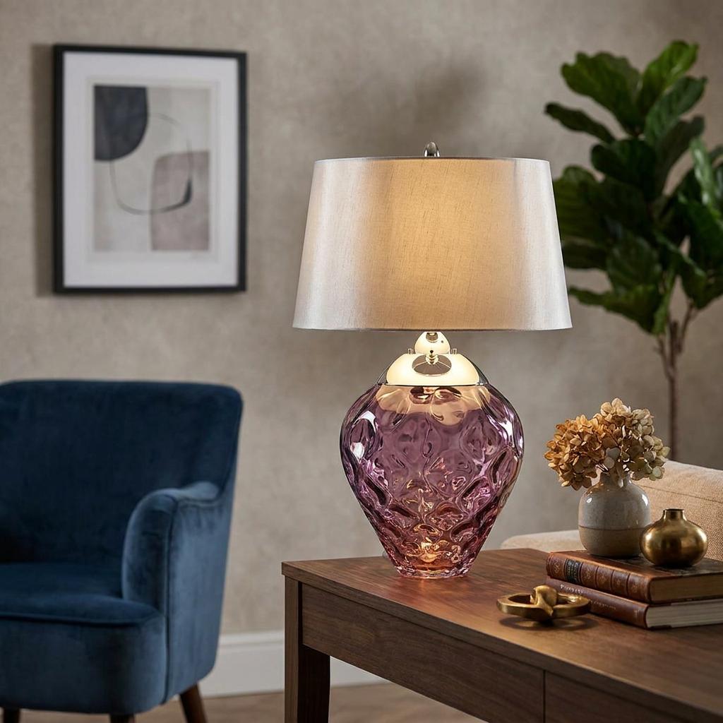 Lit Samara Plum Glass Table Lamp featuring a textured purple base and silver shade on a wooden side table.