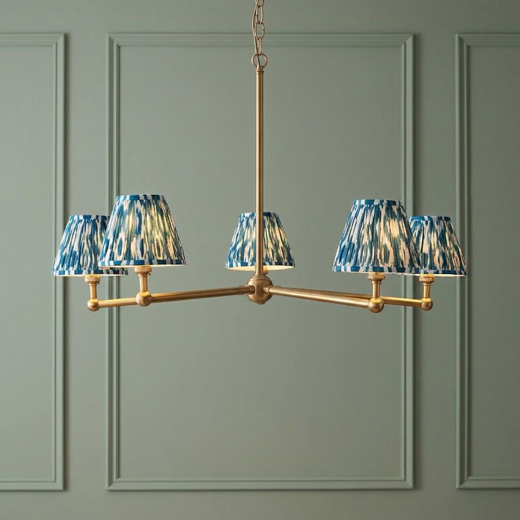 Santiago brass 5-light pendant with blue ikat shades against a sage green paneled wall.