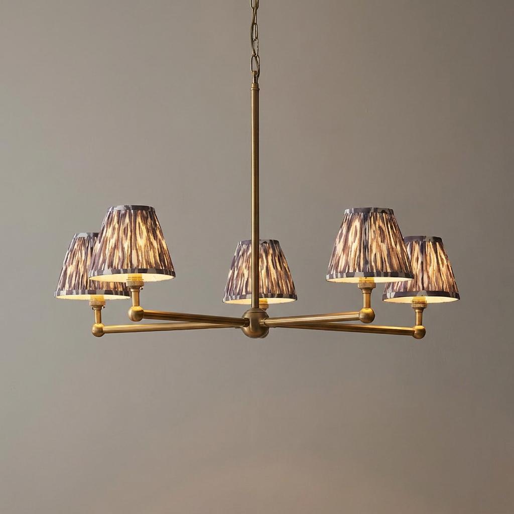 Five-light brass pendant chandelier with grey ikat fabric shades on extended horizontal arms.