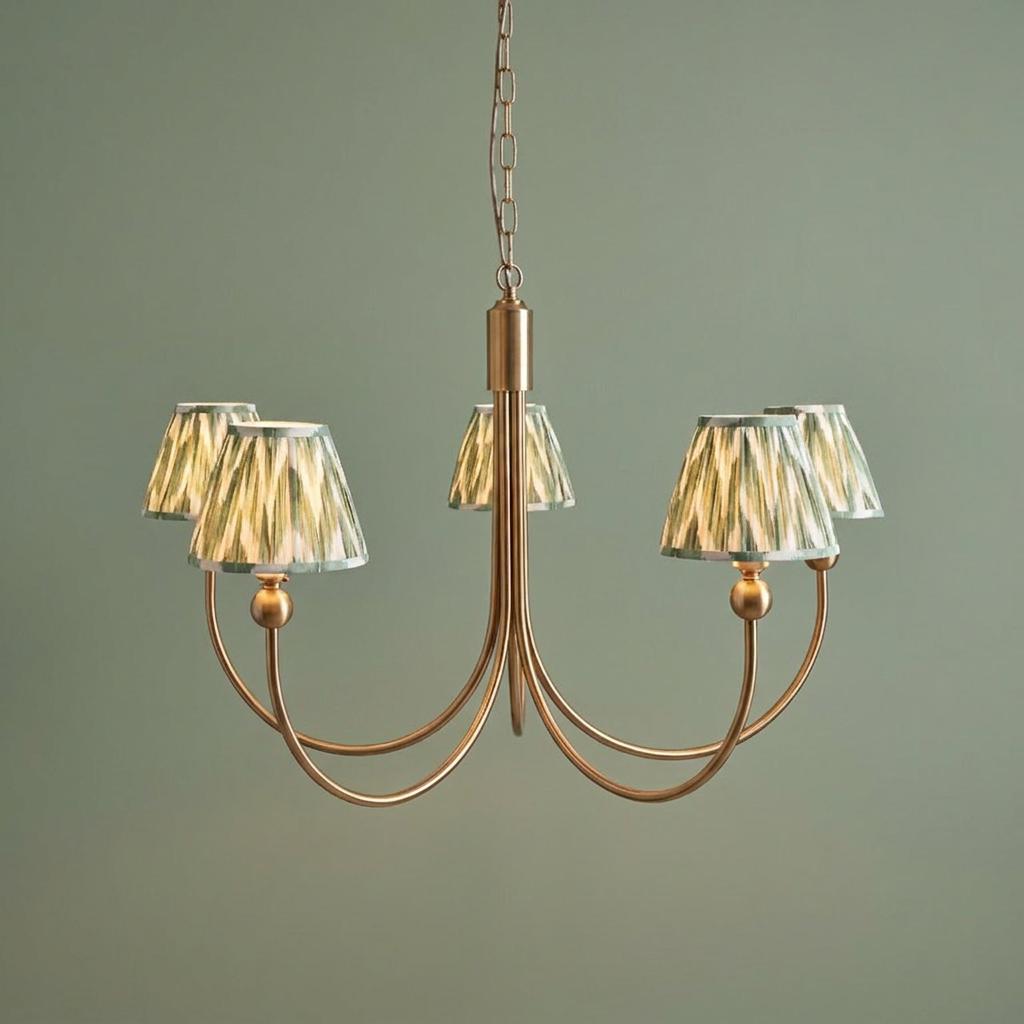 Santiago brass chandelier with five green zigzag patterned shades against a sage green wall.