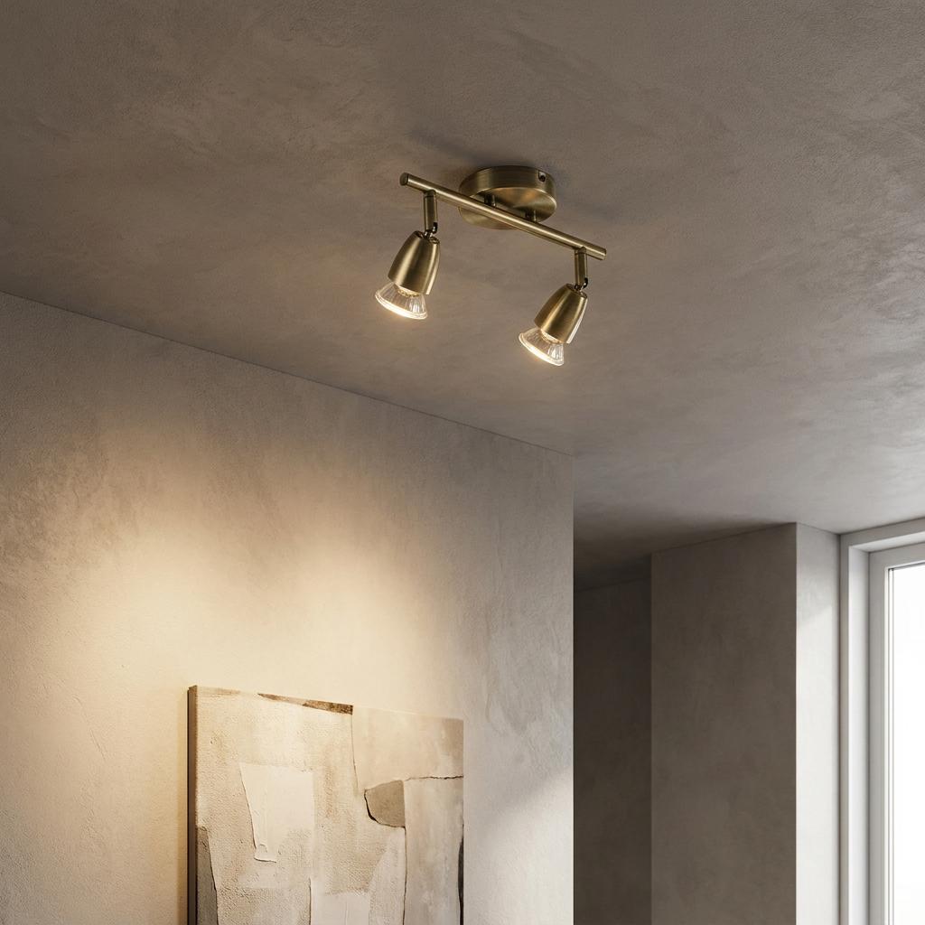 Antique brass 2-light ceiling spotlight bar illuminating a textured wall and abstract painting in a modern room.