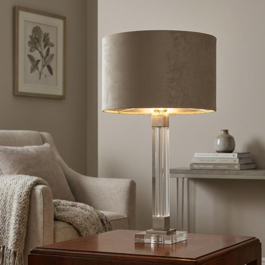 Crystal and satin nickel table lamp with a taupe velvet shade in a neutral-toned living room.