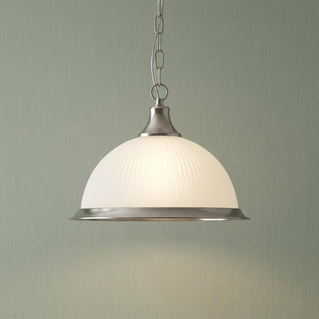 Ribbed white glass dome pendant light with silver metal accents suspended by a chain against a neutral wall.