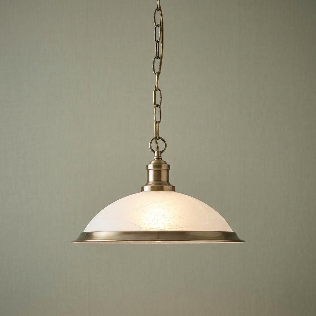 Antique brass pendant light with a frosted glass dome shade hanging from a chain against a plain green wall.