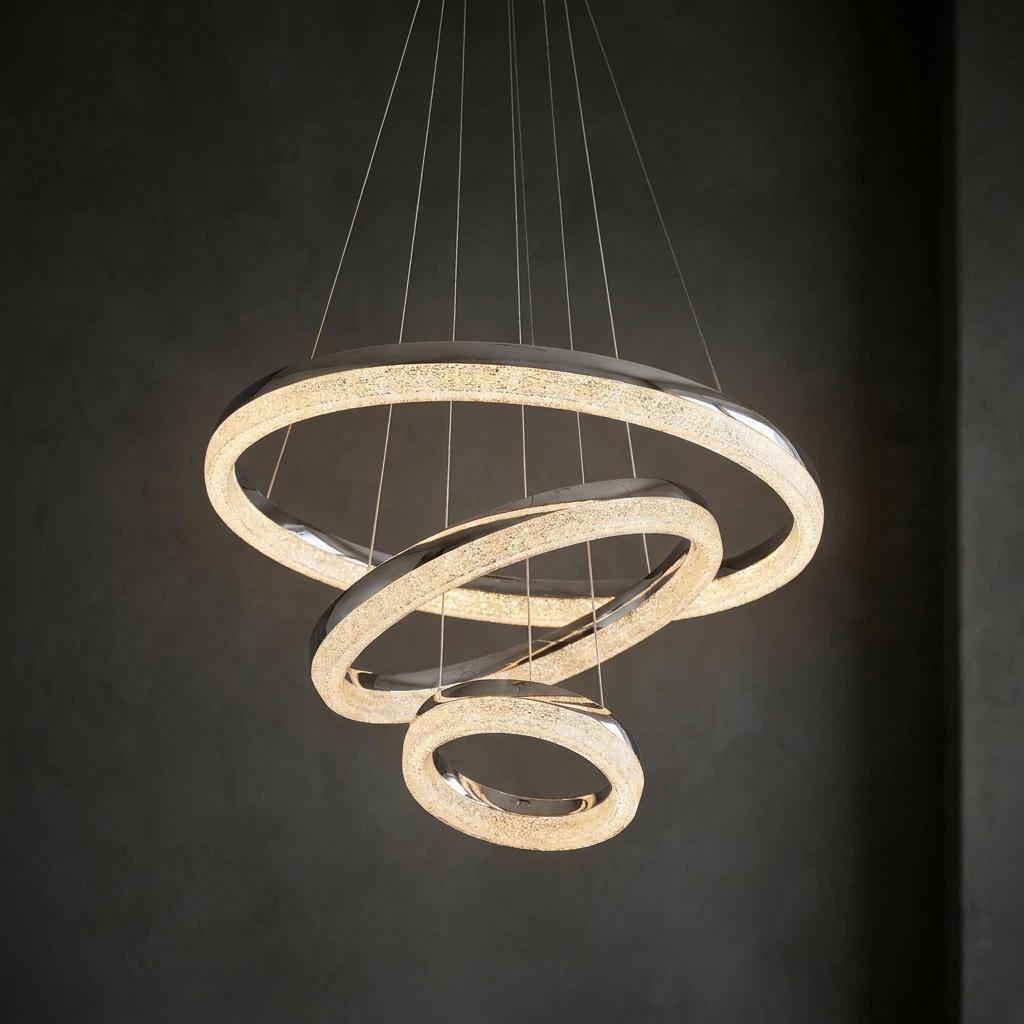 Modern chrome three-tier LED ring pendant with crushed ice effect glowing against a dark textured wall.