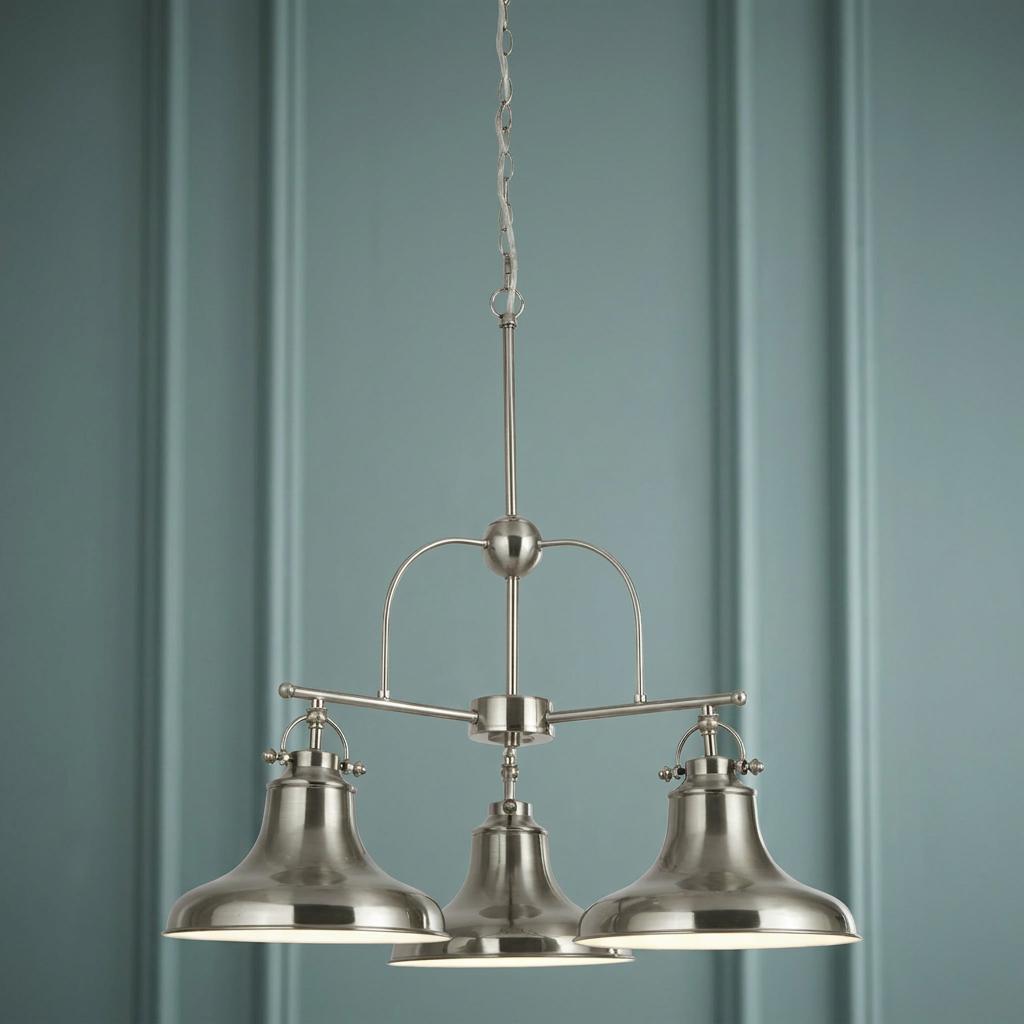 Three-light satin silver pendant with industrial bell shades hanging against a blue-green paneled wall.