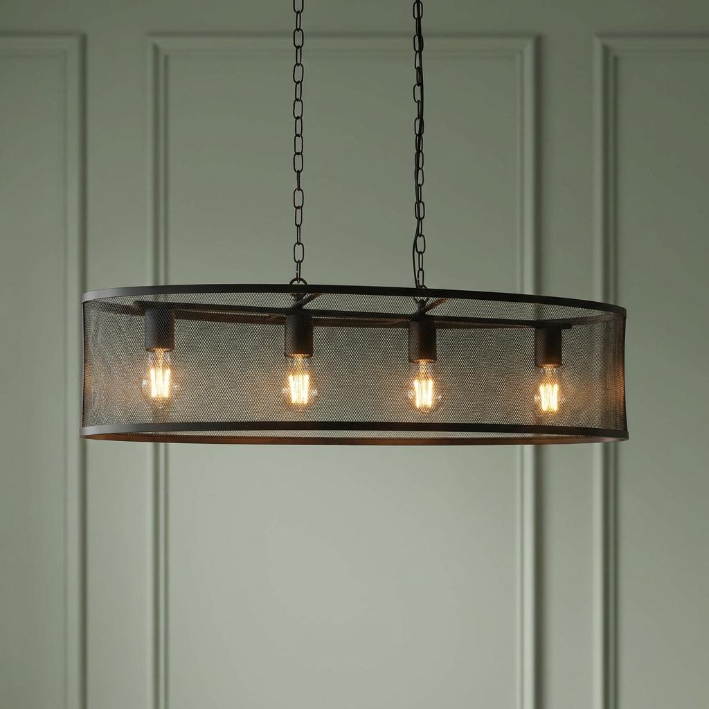 Four-light black mesh drum pendant with glowing bulbs suspended by chains in front of a green paneled wall.