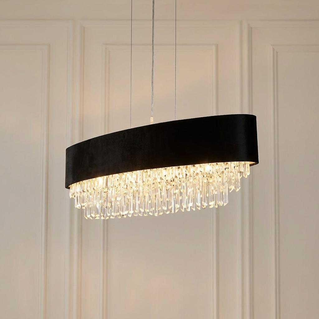 Oval pendant light with a black velvet shade and tiered crystal droplets against a paneled wall.