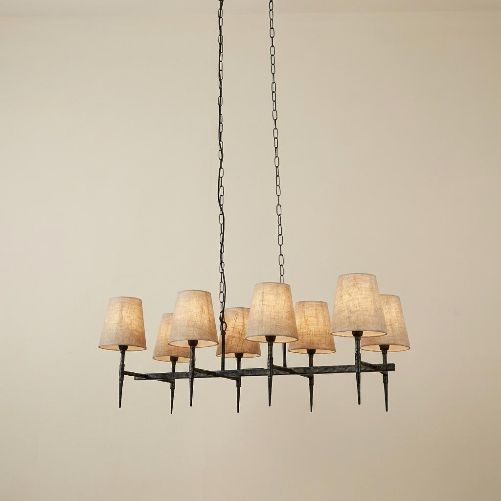 Gothic 8-light linear chandelier in hammered black finish with natural linen shades suspended by chains.