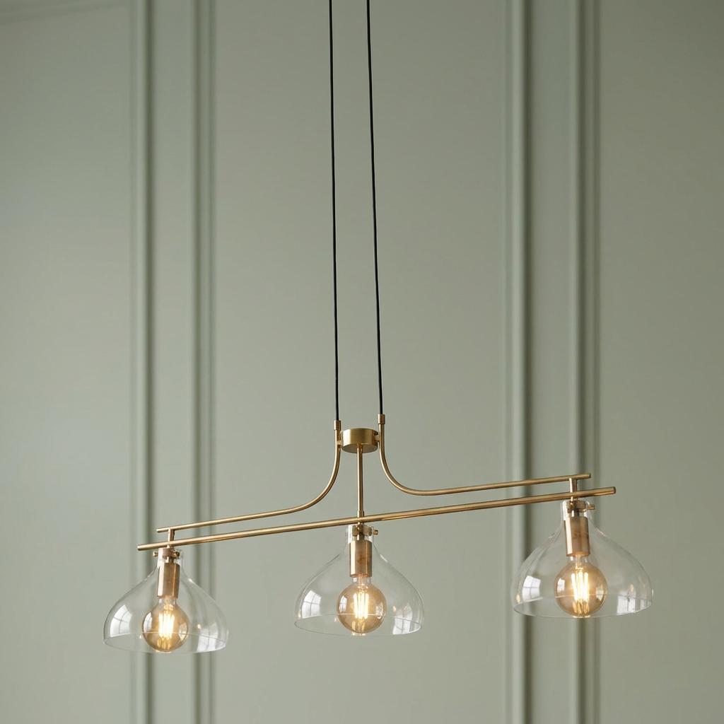 Searchlight Margarita 3-light brass bar pendant with clear glass shades hanging against a green paneled wall.