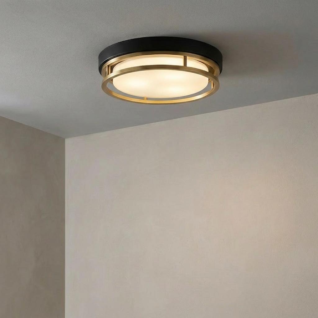 Round flush ceiling light with black base, gold-finished metal rings, and opal glass diffuser.
