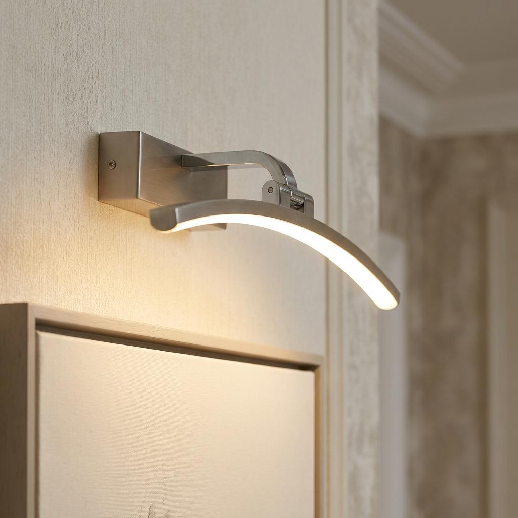Sleek silver curved LED picture light fixed to a wall, illuminating a framed canvas.
