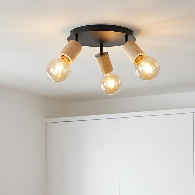 Modern 3-light ceiling spotlight with black base and wood sockets over a kitchen counter with warm globe bulbs.