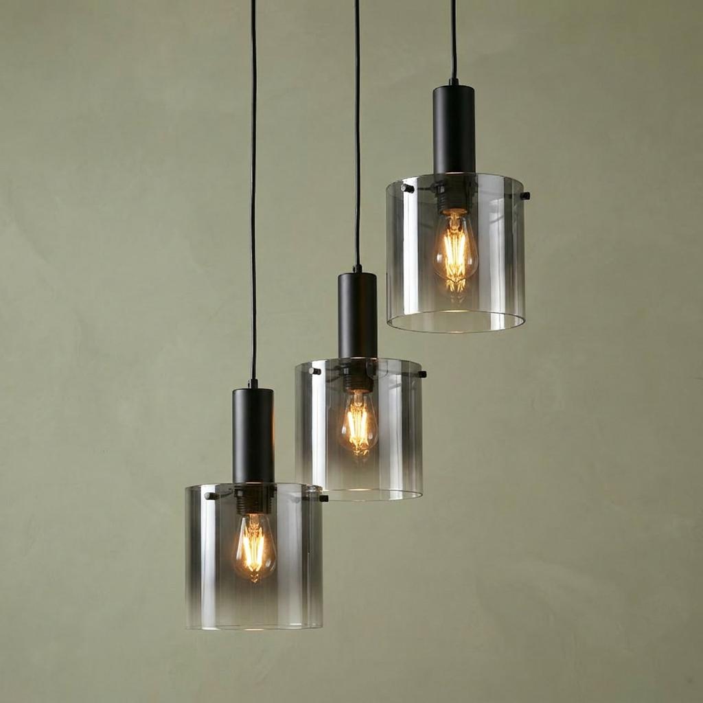 Three black pendant lights with smoked ombre glass shades hanging at staggered heights against a textured green wall.