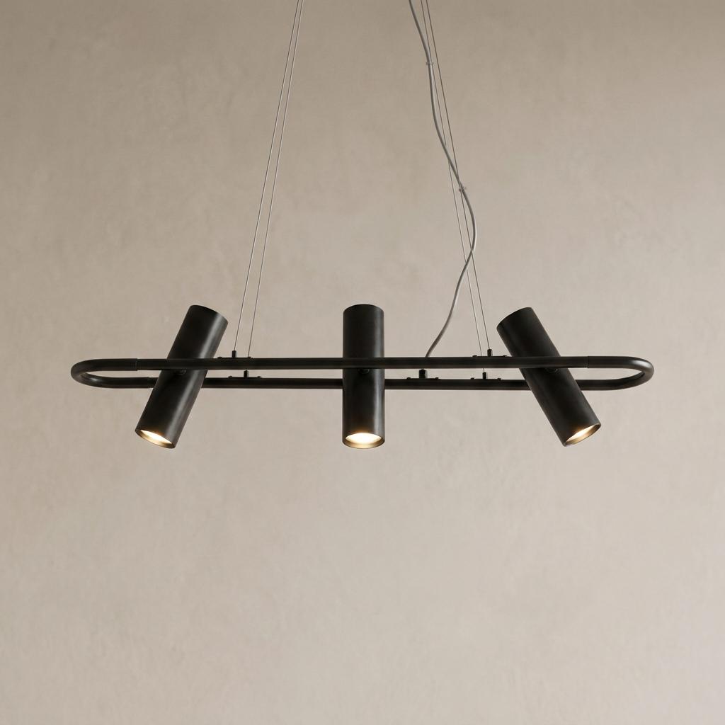 Three black cylindrical spotlights on a minimalist horizontal oval track suspended against a neutral background.