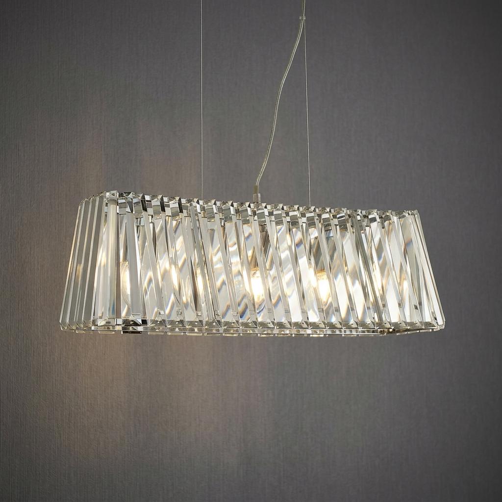 Rectangular chrome pendant light with vertical crystal prisms illuminated against a dark grey textured wall.