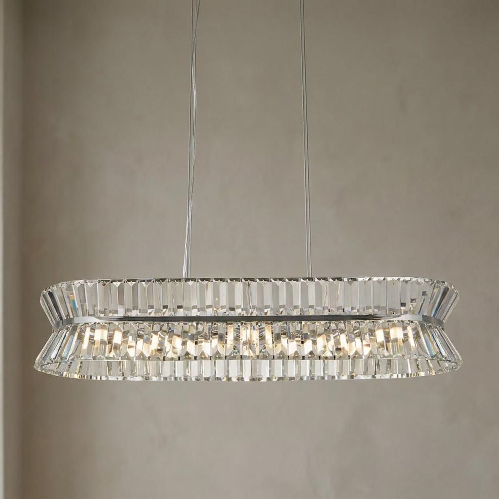 Oval chrome and crystal pendant light with faceted glass prisms, suspended against a light textured wall.