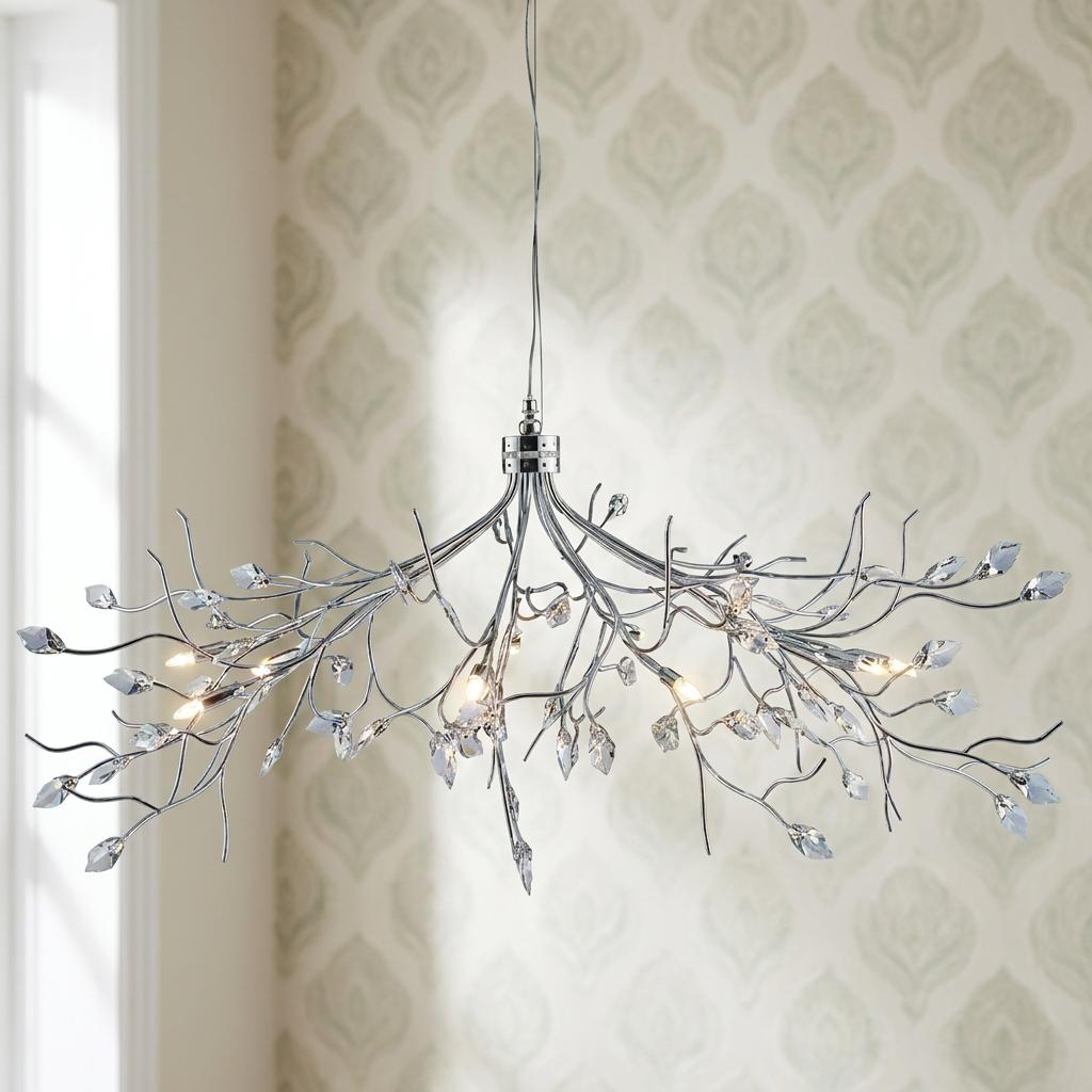 Chrome branch-style ceiling pendant with crystal leaf accents and eight glowing bulbs against a patterned wall.