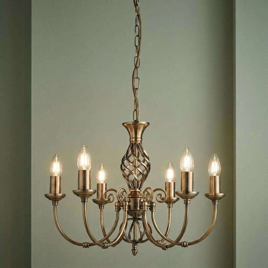Antique brass 6-light chandelier featuring a twisted cage column and scroll arms against a green wall.