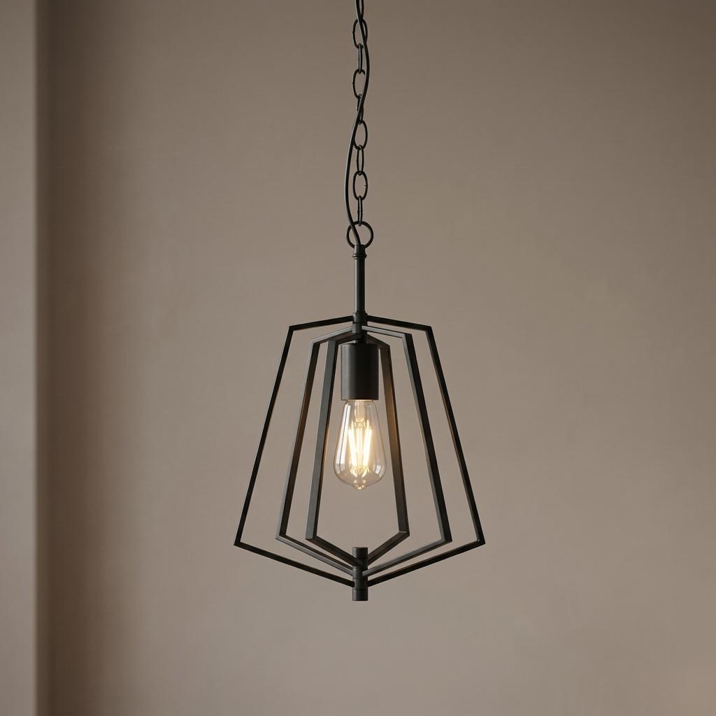 Black metal geometric pendant light with a lit Edison bulb hanging from a chain against a neutral wall.