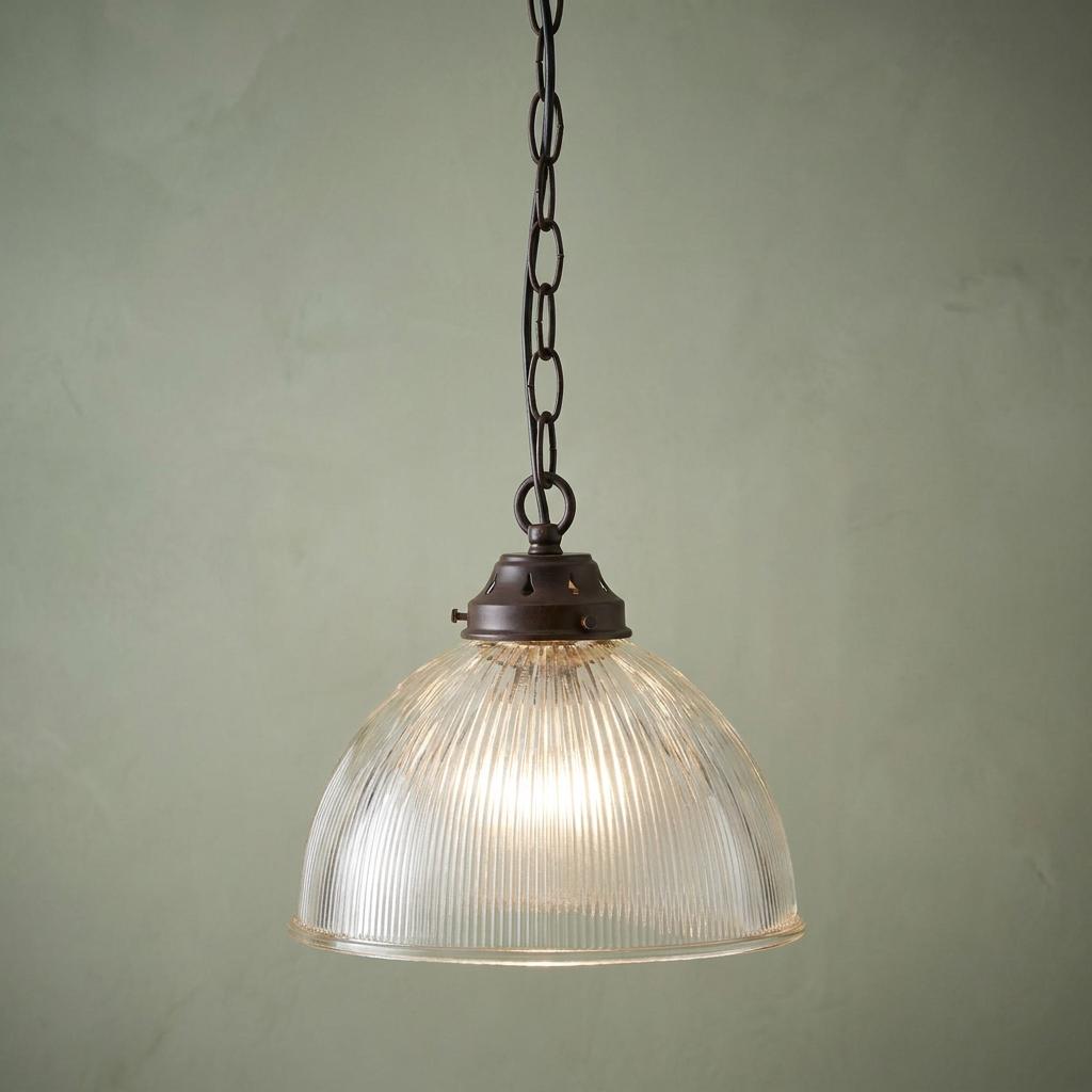 Small prismatic glass dome ceiling light with a bronze chain and gallery, illuminated against a pale green wall.