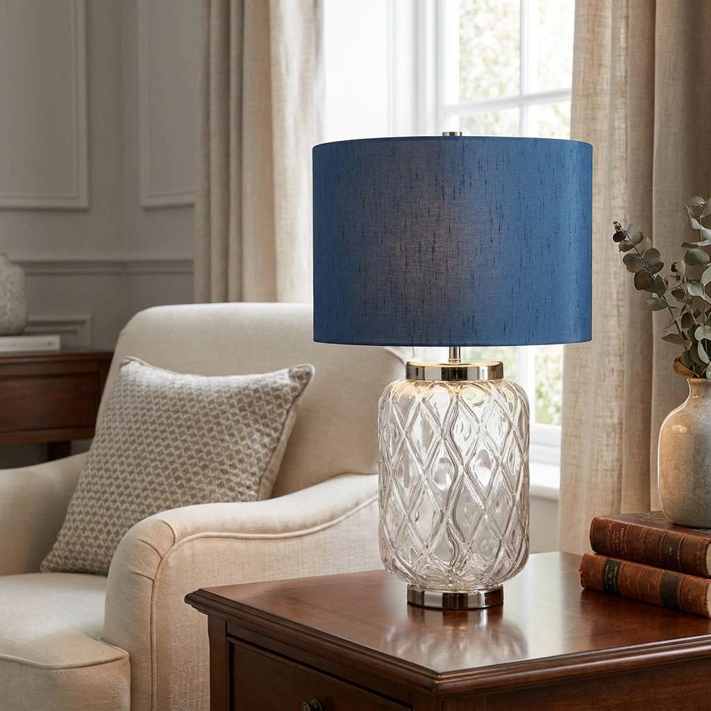 Sola 1 light glass table lamp with a blue fabric shade and diamond-patterned clear glass base on a side table.