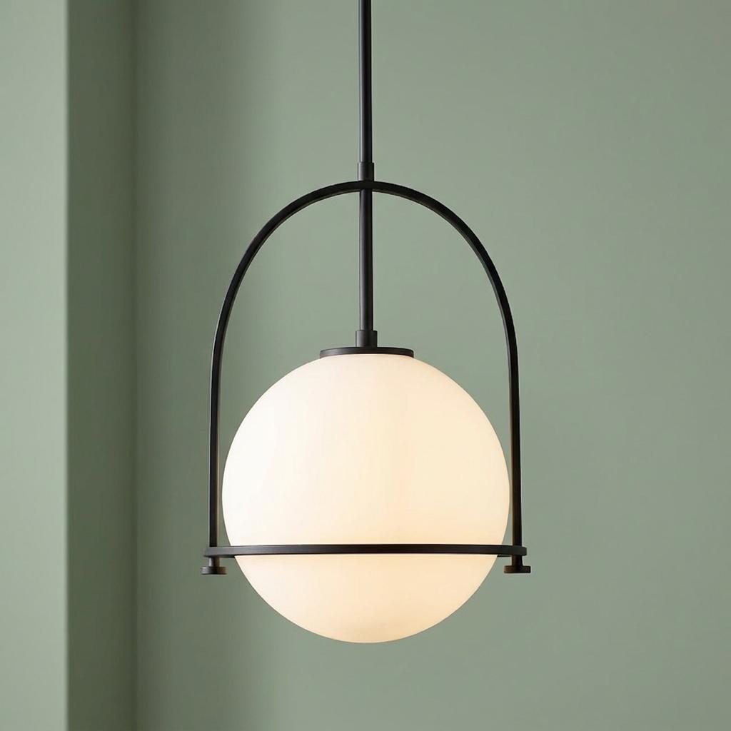 White opal glass globe pendant light within a black arch frame against a sage green wall.