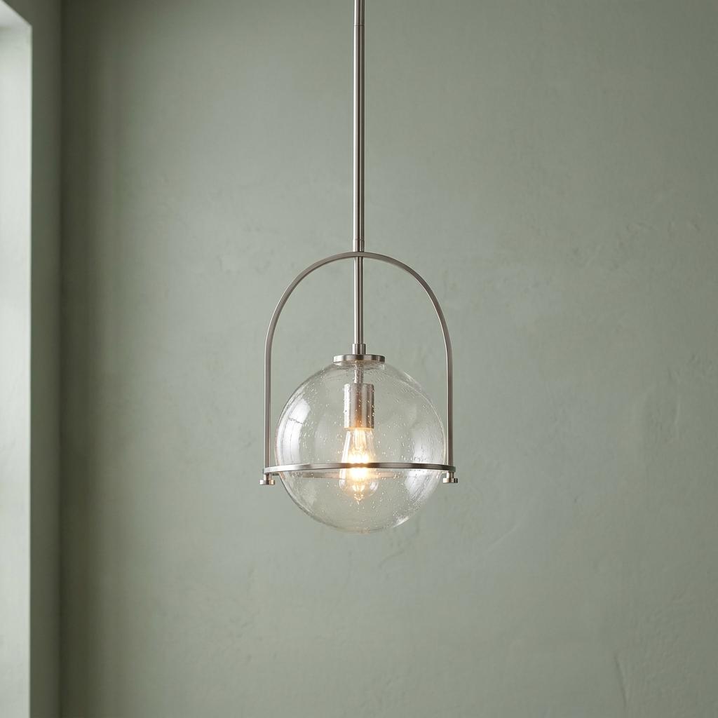 Somerset nickel pendant light with a clear seeded glass globe and arched frame against a soft green wall.