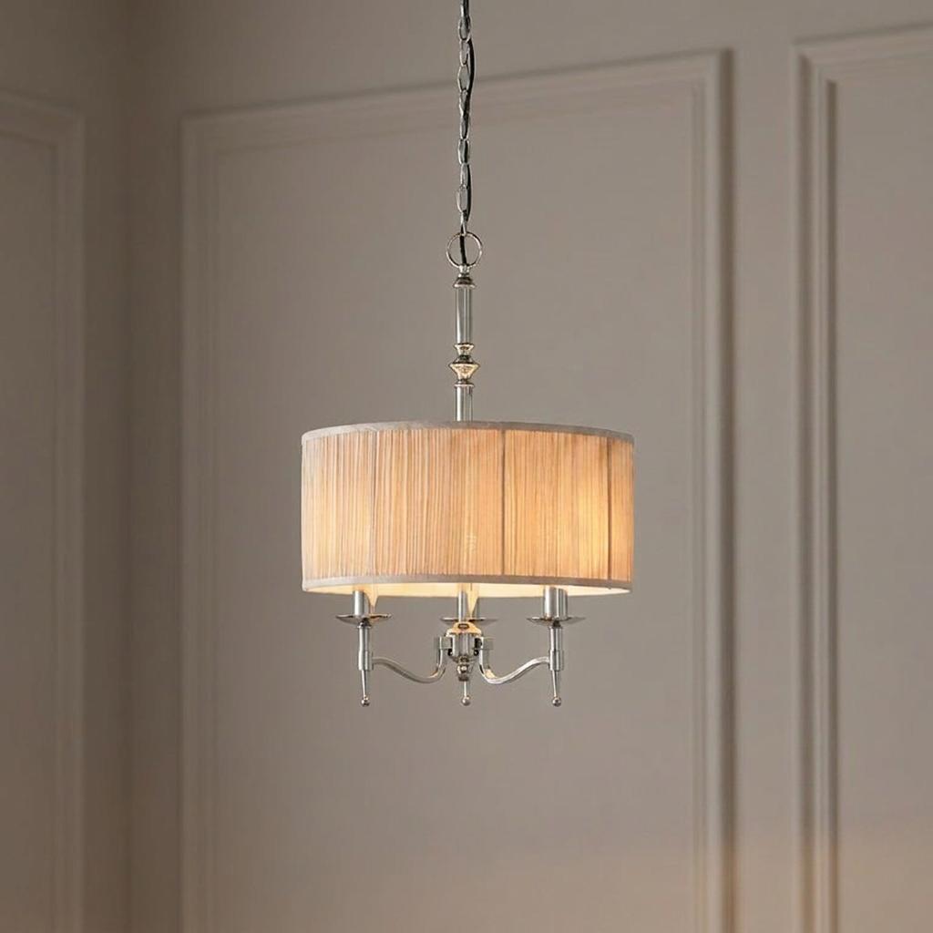 Stanford polished nickel 3-light pendant with a beige pleated drum shade hanging against a neutral paneled wall.