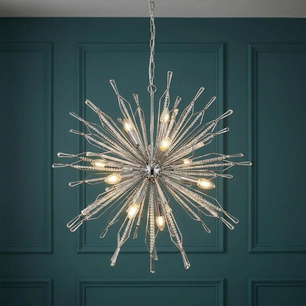 Starburst 10 light chrome and crystal glass ceiling pendant illuminated against a dark teal paneled wall.