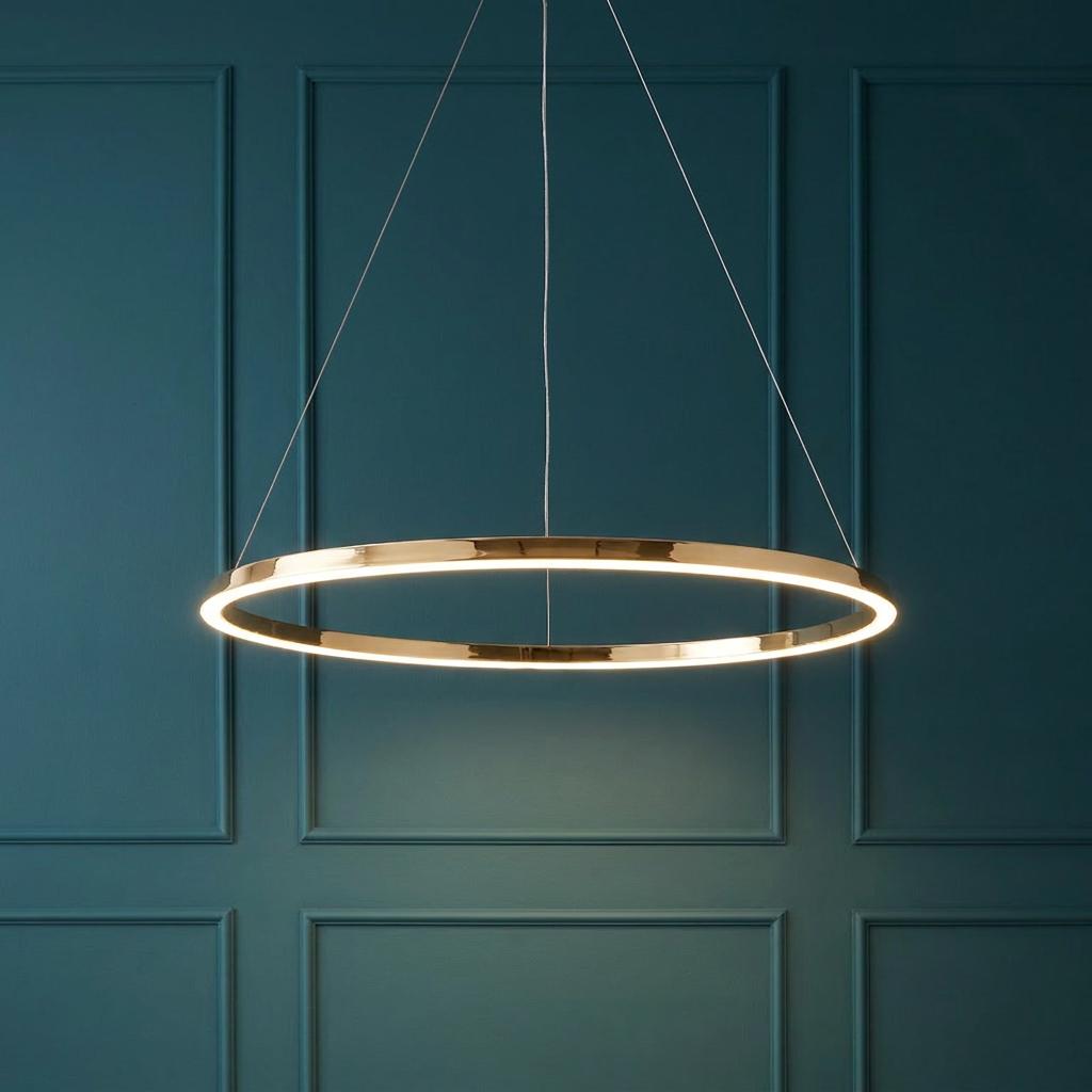 Staten gold halo pendant light glowing against a teal paneled wall.