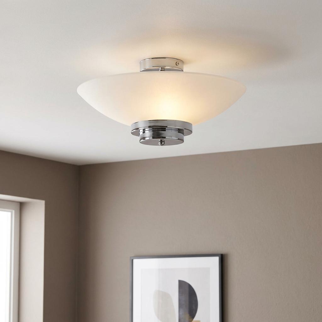 Art Deco flush ceiling light with a frosted white bowl shade and tiered chrome base, glowing on a white ceiling.