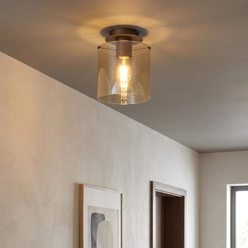 Sweden mocha flush ceiling light with an amber glass cylindrical shade illuminates a hallway with soft warm light.