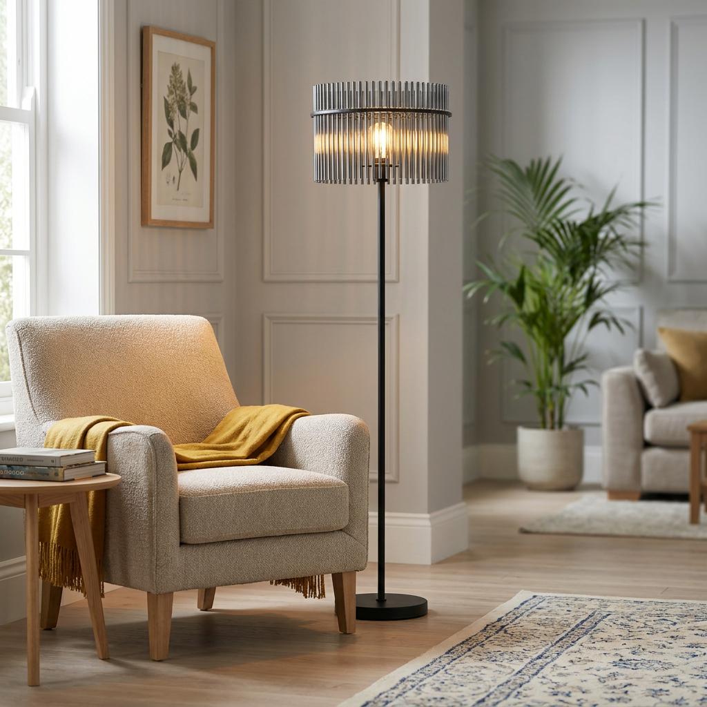 Matte black floor lamp featuring a smoked glass rod shade, positioned next to an armchair in a modern living room.