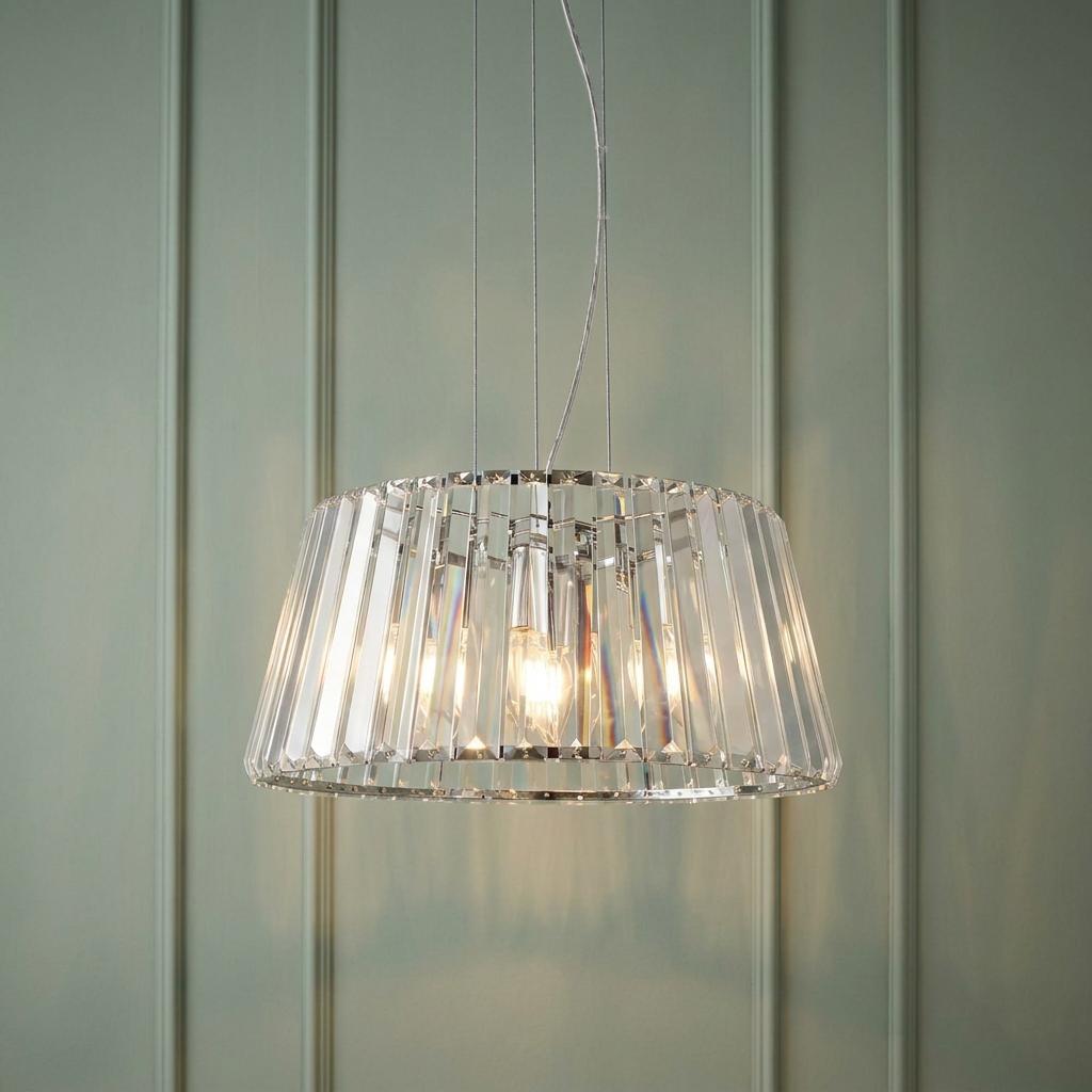 Elegant 5-light chrome and clear crystal glass pendant light hanging against a soft green paneled wall.