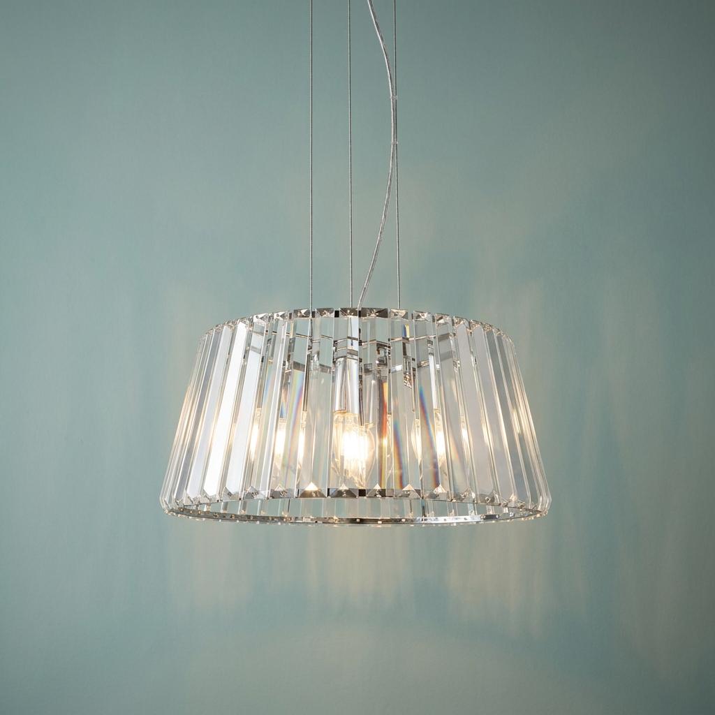 Tiara 5-light chrome ceiling pendant with vertical clear glass rods illuminated against a light blue wall.