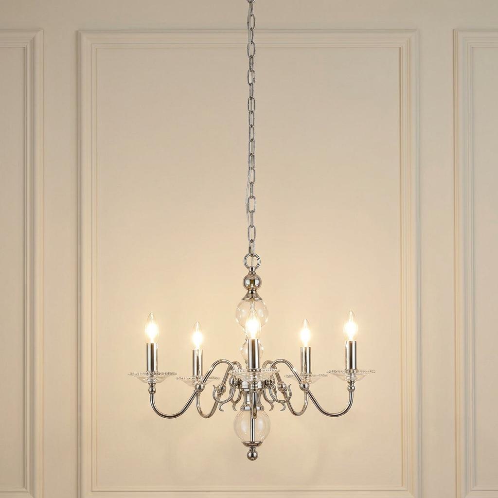 Tilburg 5-light chandelier in polished nickel with illuminated bulbs, hanging against a paneled cream wall.