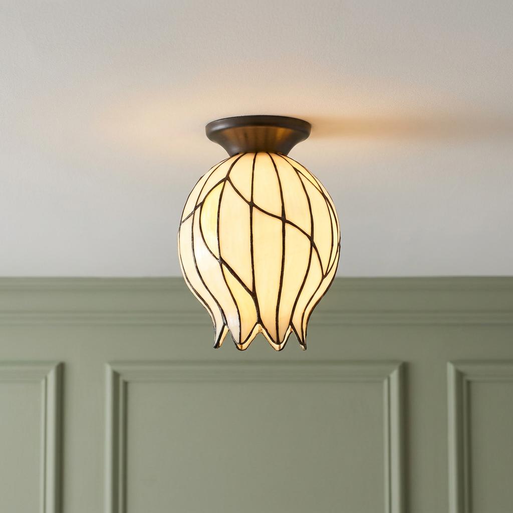 Tulip-shaped Tiffany flush ceiling light with cream glass panels and bronze mount against a green paneled wall.